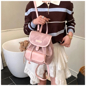 Detail of dusty pink vintage backpack with magnetic flap and cute brown teddy bear charm