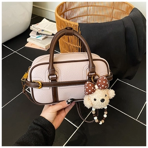 Detail of pink lychee leather handbag with brown handles and a cute dog plush charm