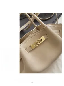 Detailaufnahme des goldenen Metallverschlusses an der gefalteten beigen Lederhandtasche
