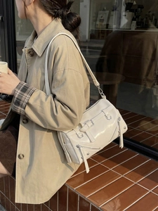 Chic cream white crossbody bag with silver zippers and rivet details on a model