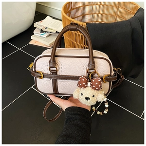Detail of Boston bag with pink and brown stitching, featuring a plush dog charm