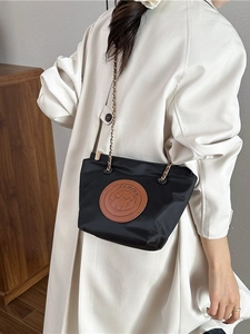 Sac seau chic en nylon noir avec écusson en cuir chiot et chaîne dorée sur modèle