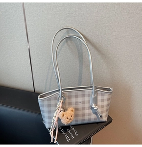 Detail of silver plaid tote bag featuring logo print and cute plush bear charm