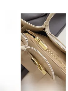 Nahaufnahme der beigen Lederhandtasche mit goldenem Reißverschluss und Lychee-Struktur