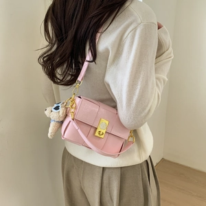 Détail du sac en cuir tressé rose avec boucle dorée et breloque ours sur modèle