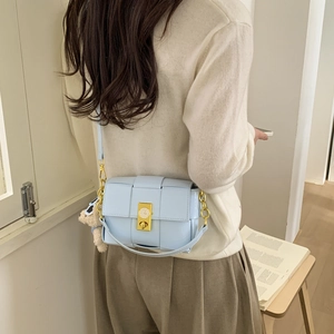 Détail du sac tressé bleu clair avec fermoir horloge doré et breloque ours en peluche