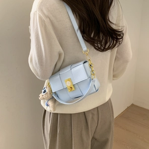 Détail du sac à main bleu clair en cuir tressé avec fermoir doré et charme d'ours
