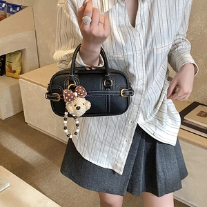 Close-up of black pebble leather tote with contrast stitching and bear charm detail