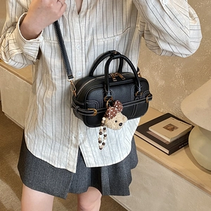 Detail of black pebbled leather mini Boston bag with white stitching and bear charm