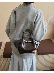 Details der glänzenden dunkelbraunen Lederhandtasche mit eleganter goldener Metallschnalle