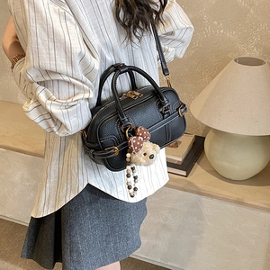 Detail of black pebbled leather Boston bag with white stitching and bear charm