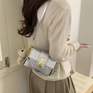 Détail du sac bandoulière en cuir tressé argenté avec breloque ours et fermoir doré