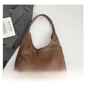 Detail view of brown vintage leather tote with silver eyelets and a wide shoulder strap