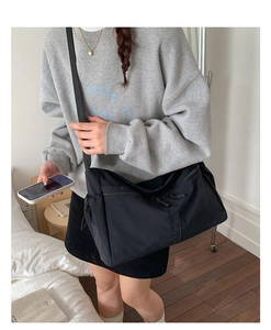 Détail du sac bandoulière en nylon noir avec sangle réglable et poche latérale à cordon