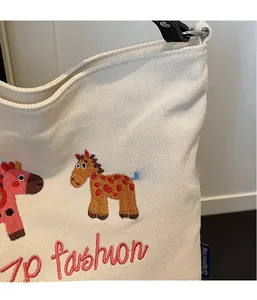 Close-up of canvas tote bag featuring colorful giraffe embroidery and red logo lettering