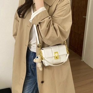 Gros plan du sac blanc tressé avec boucle dorée et pendentif ours en peluche mignon
