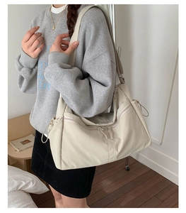 Detail of light beige nylon crescent bag with adjustable strap and side drawstring pockets