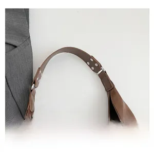 Detail of brown leather strap with silver rivets and metal ring on a shoulder bag