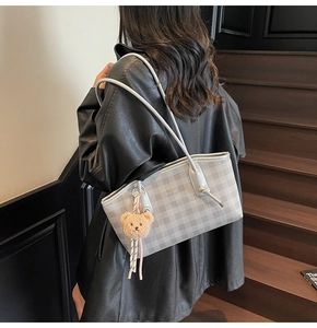 Détail du sac cabas à damier argenté avec pendentif ours en peluche et bandoulières nouées