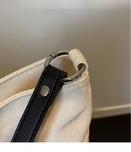 Close-up of shiny silver metal rings connecting black leather straps to the canvas tote