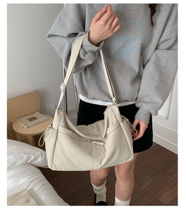 Détail du sac besace en nylon blanc cassé avec poches zippées et bandoulière réglable
