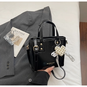 Detail of black bucket bag with pearl heart charm and lace bow on a blazer