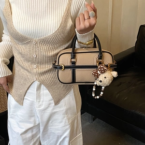 Detail of beige and black boston bag with litchi grain leather and teddy bear charm