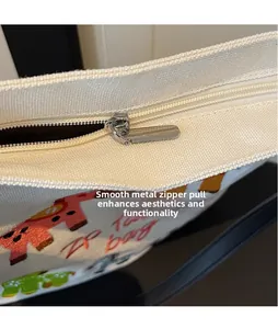 Close-up of silver metal zipper and colorful embroidery on cream canvas tote bag