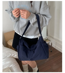 Detail of navy blue nylon hobo bag featuring multiple side pockets and a wide strap