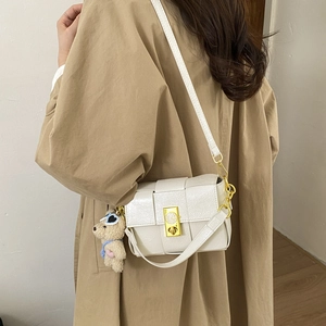 Détail du sac à main blanc en cuir brillant avec serrure horloge et porte-clé ours