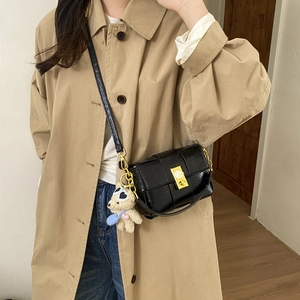 Sac bandoulière en cuir verni noir avec fermoir doré et breloque ours sur modèle