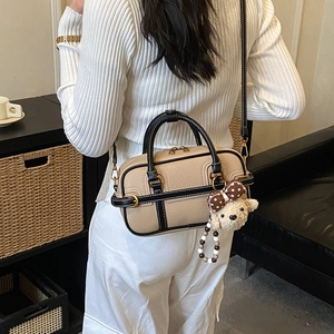 Detail of two-tone boston bag with teddy charm in cozy home lifestyle setting