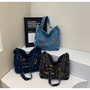Close-up of embroidered denim tote bags in light blue, dark blue, and black grey colors
