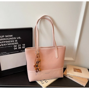 Dettaglio della borsa tote rosa con logo del marchio e ciondolo in perline etniche