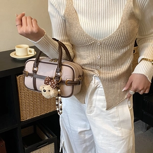 Detail of Boston bag showing pink lychee leather with teddy bear charm and beaded strap