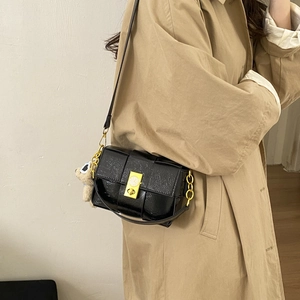 Détail du sac à main tissé noir avec boucle dorée et accessoire ours en peluche doux