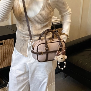 Detail of pink pebbled leather Boston bag with teddy bear charm and brown handles