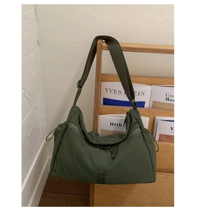 Detail of olive green large nylon tote bag featuring side drawstrings and smooth zipper