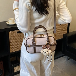 Detail of lychee pattern leather bag with plush puppy charm and golden metal buckle