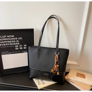 Dettaglio borsa tote in pelle nera con cuciture a contrasto bianche e ciondolo di perline