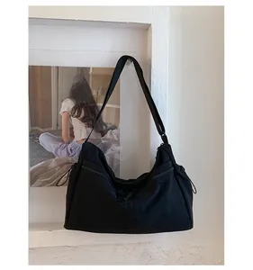 Gros plan du sac en nylon noir avec bandoulière réglable et détails de cordon latéral