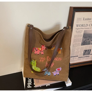 Detail of colorful cartoon pony embroidery and brown synthetic leather straps on hobo bag