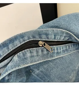 Detailed macro view of smooth black zipper and washed blue denim texture on tote bag