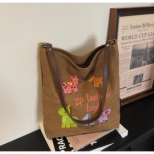 Detailed view of canvas tote bag featuring colorful animal embroidery and dark leather straps