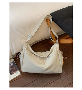 Détail du sac bandoulière en nylon avec double zip frontal et poches latérales à cordon
