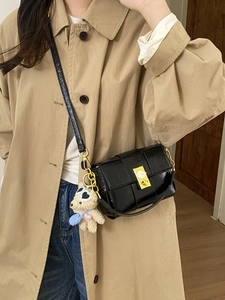 Sac bandoulière en cuir verni tissé noir avec boucle dorée et breloque ourson