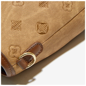 Macro view of textured monogram fabric and premium gold metal hardware on the bucket bag