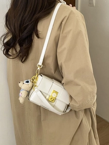 Sac bandoulière beige en cuir tressé avec boucle dorée et breloque ours en peluche