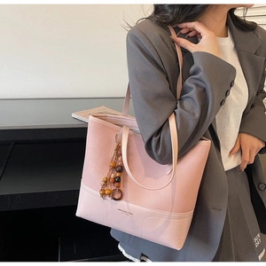 Dettaglio della borsa rosa con inserto in pelle scamosciata e nappa di legno
