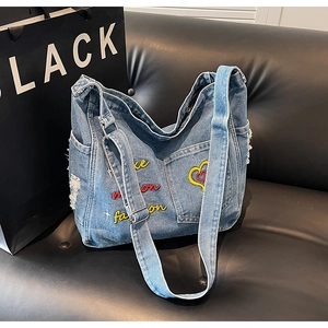 Detail of embroidered heart pattern and distressed denim texture on a tote bag
